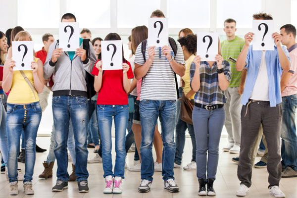 Group Of People Covering Faces With Question Mark Cards